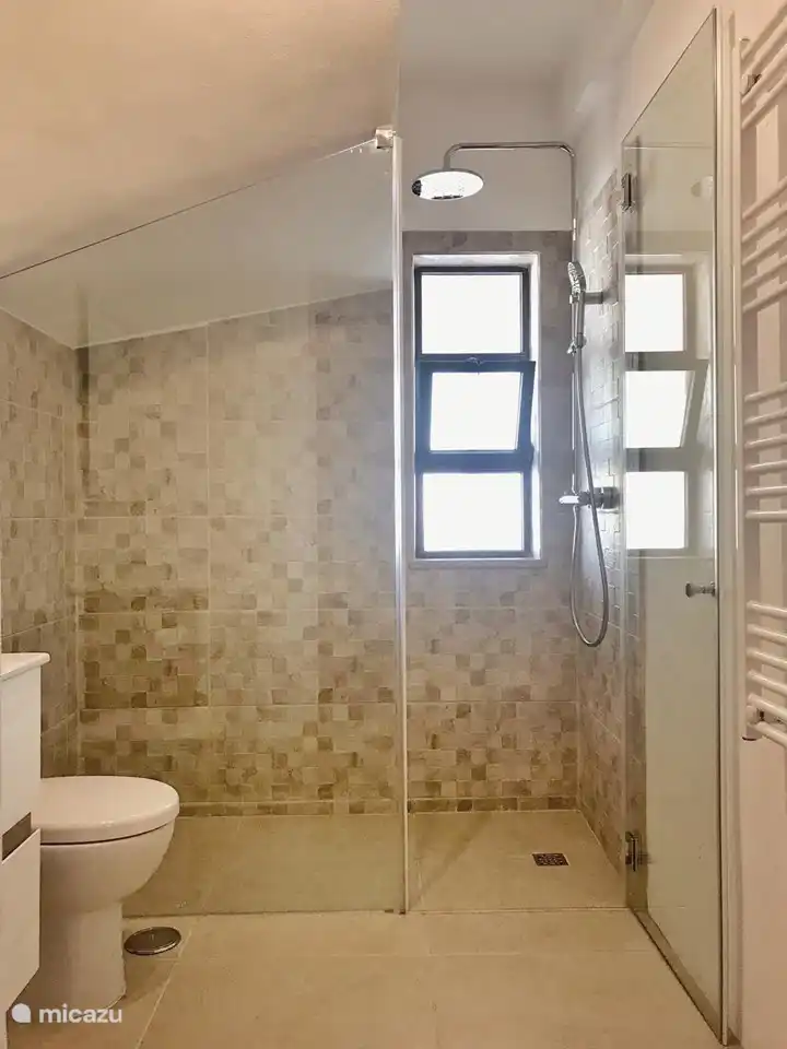 Planta baja: baño moderno con ducha a ras de suelo con radiador toallero y calefacción por suelo radiante