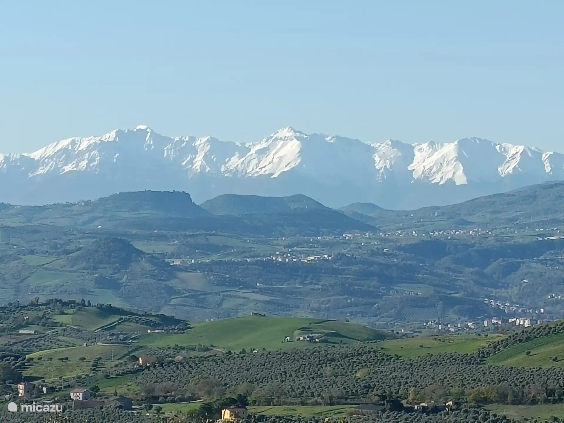 En abril de 2025, todavía hay abundante nieve en las cumbres de los Apeninos. En primer plano, parte de los 13.000 olivos del agricultor de aceite de oliva ecológico Conca d'Oro