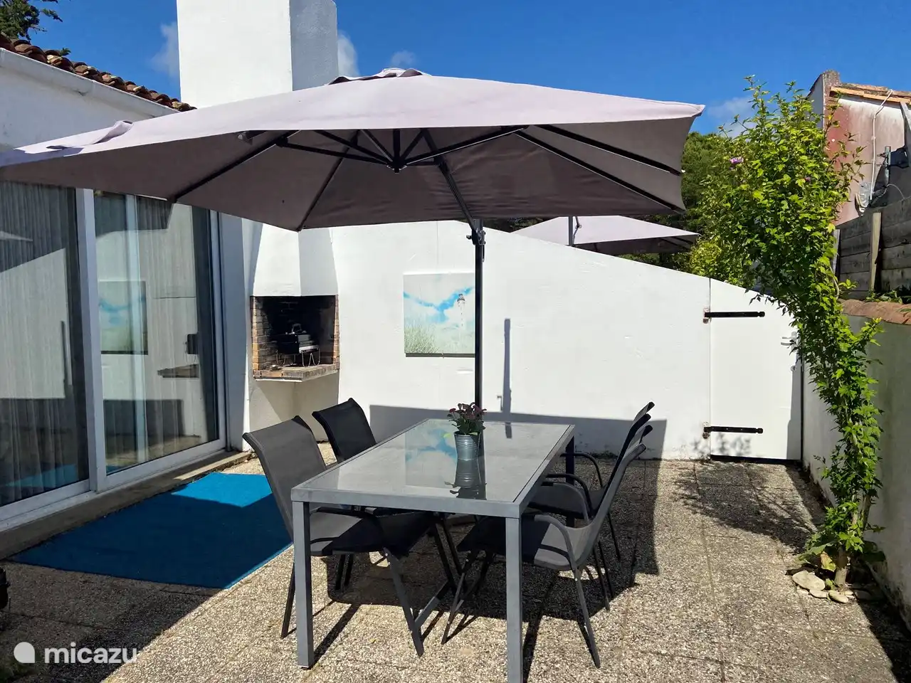 Terrace with Weber barbecue, garden furniture and cantilever parasol.