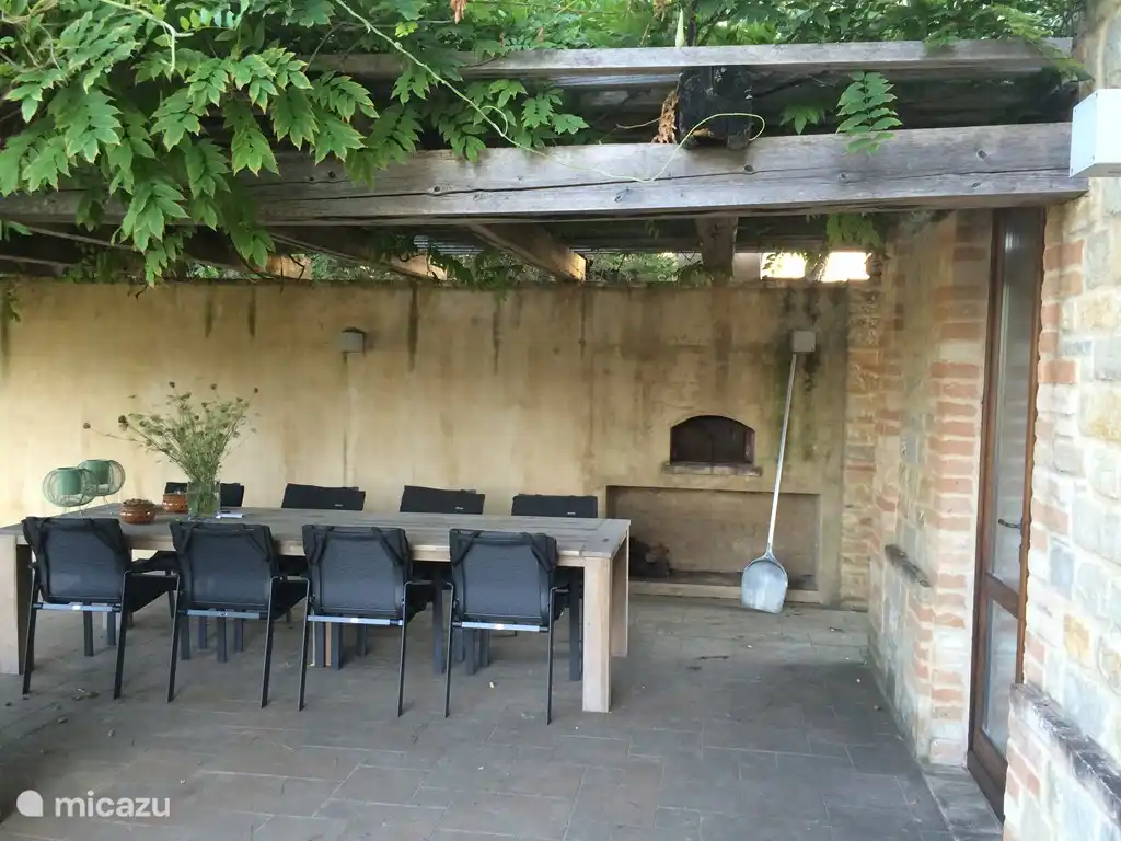 Die Terrasse vor der Küche mit großem Esstisch und Holzpizzaofen origina