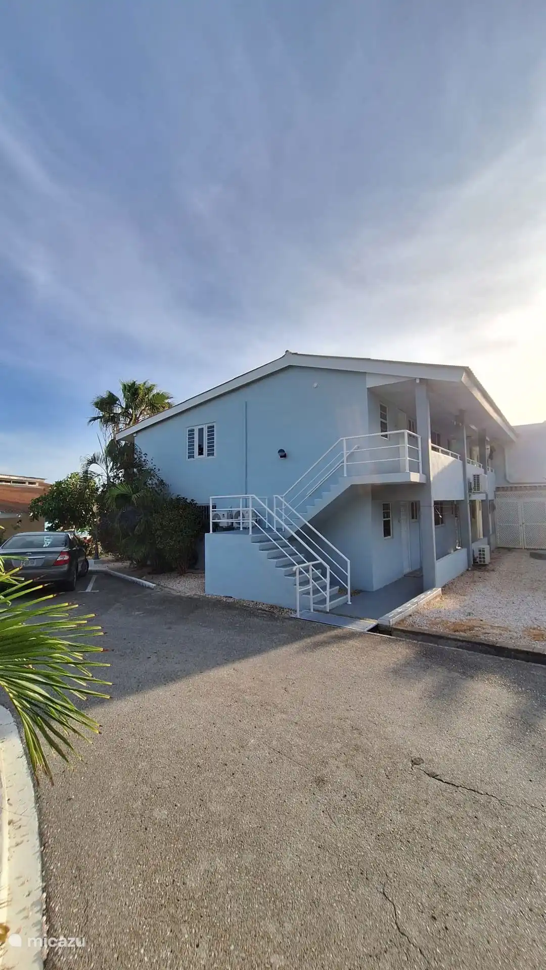 Voor zijkant van het Appartementencomplex met zicht op de trap naar boven en het zijraam. Het appartement bevindt zich direct bovenaan de trap (eerste deur)