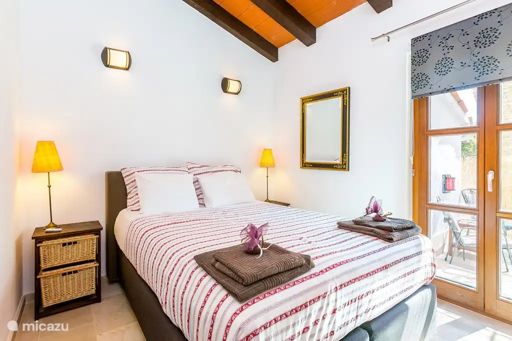 Hermoso dormitorio para dos personas con puertas de patio a un patio privado. Las puertas tienen mosquiteras retráctiles y persianas para evitar el calor.