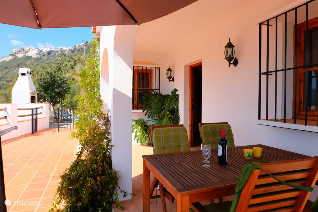 De overdekte veranda (extra stoelen zijn aanwezig).