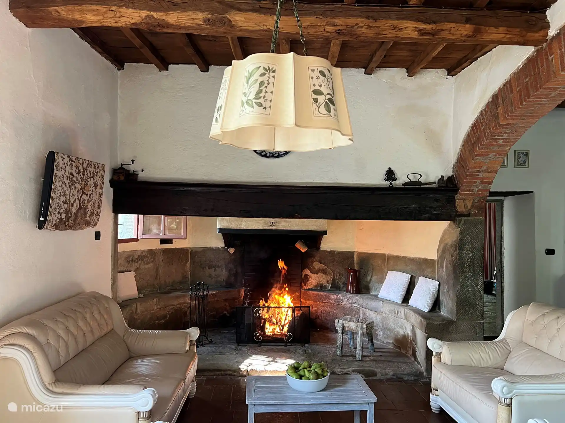 Wohnzimmer im Erdgeschoss mit großem Bauernkamin aus dem Jahr 1600. Im Wohnzimmer gibt es Sofas und Sessel, Tisch mit Stühlen, Couchtisch, einen Schrank mit Weinen, Büchern und einigen Tischspielen. 