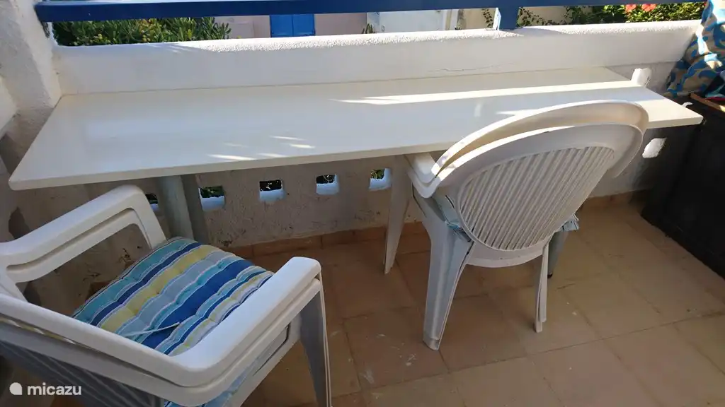 Bartafel en stoelen op balkon met zeezicht. 