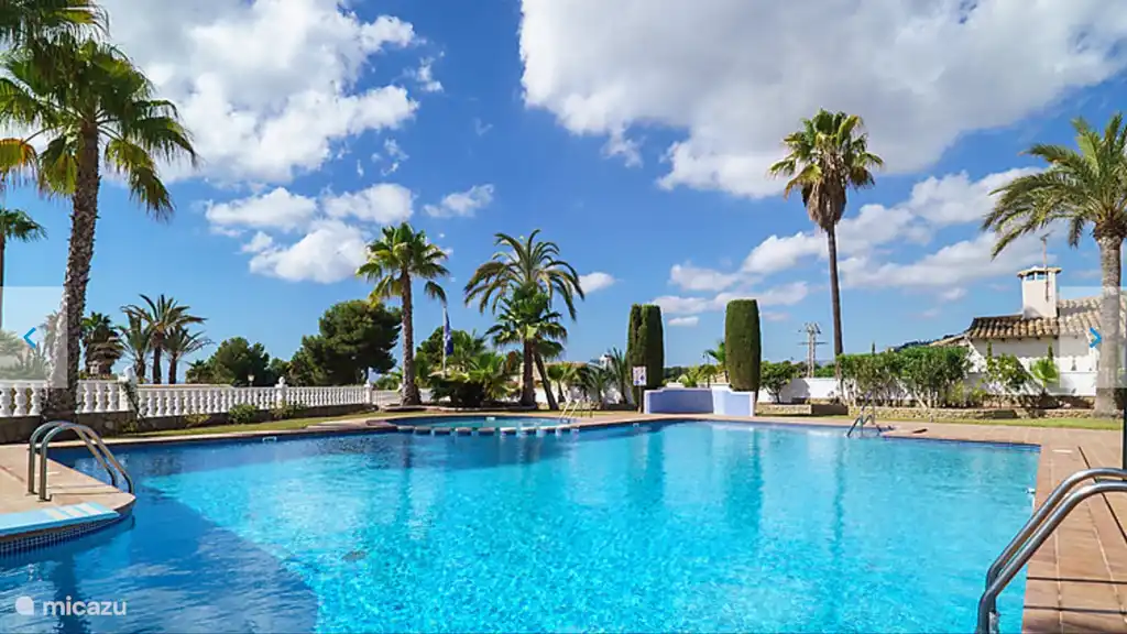 Une belle piscine partagée avec des transats.