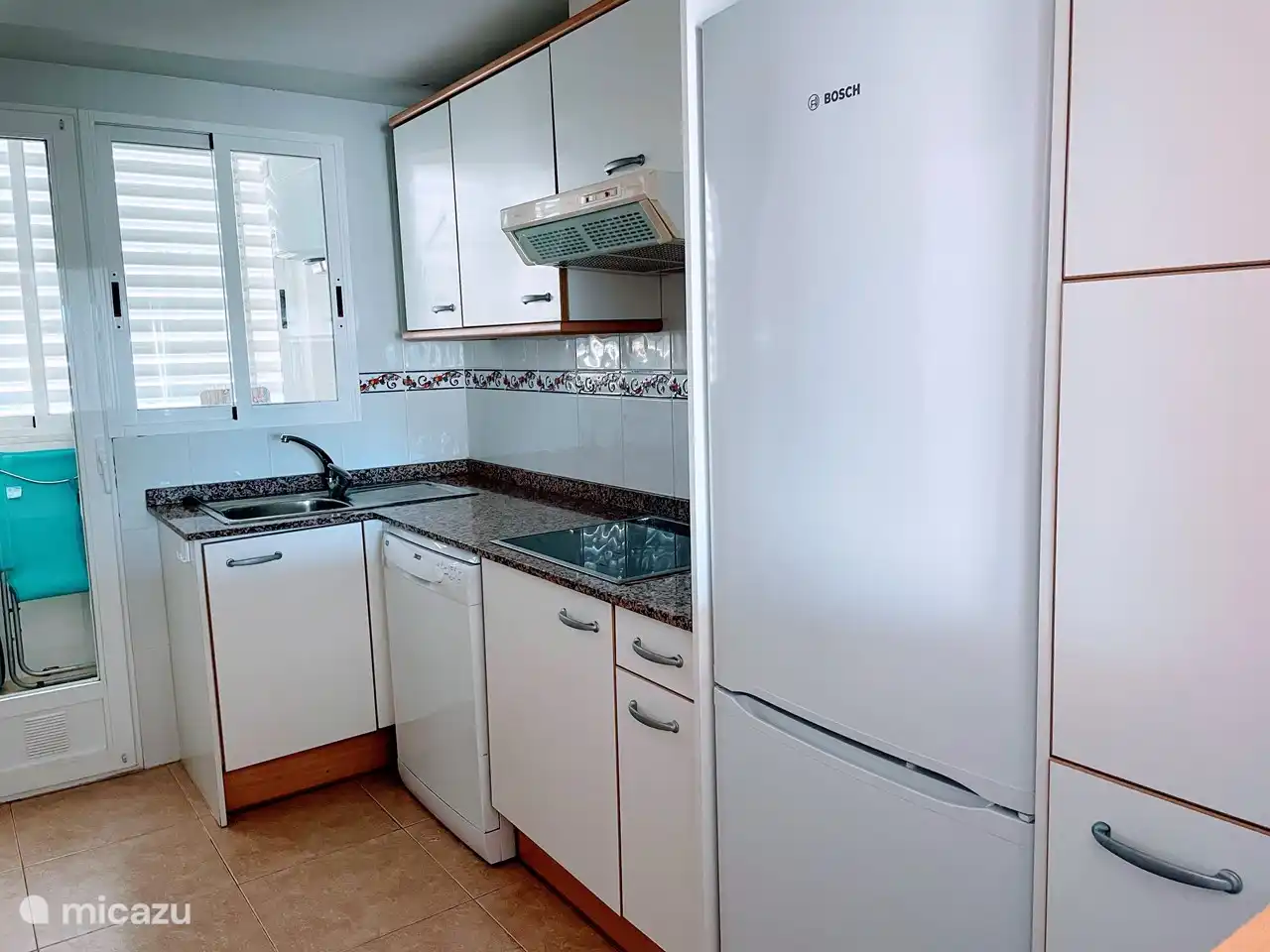 Die komplette Küche mit Geschirrspüler und Hauswirtschaftsraum mit Waschmaschine.