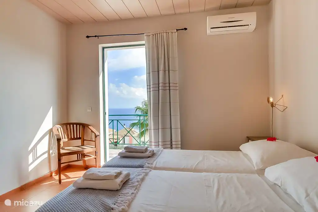 slaapkamer 2 met balcon en uitzicht op zee en badkamer ensuite