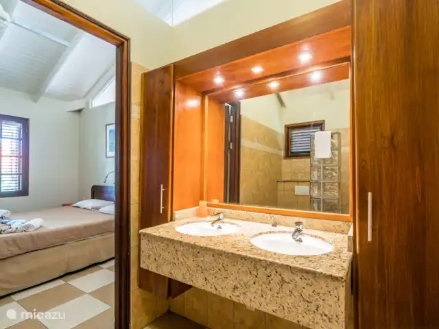 Blue Bay Beach Villa 14 en Curazao, Curazao Centro, Blue Bay - villa Dormitorio 1 con baño en suite. Se han colocado persianas de madera delante de las ventanas.