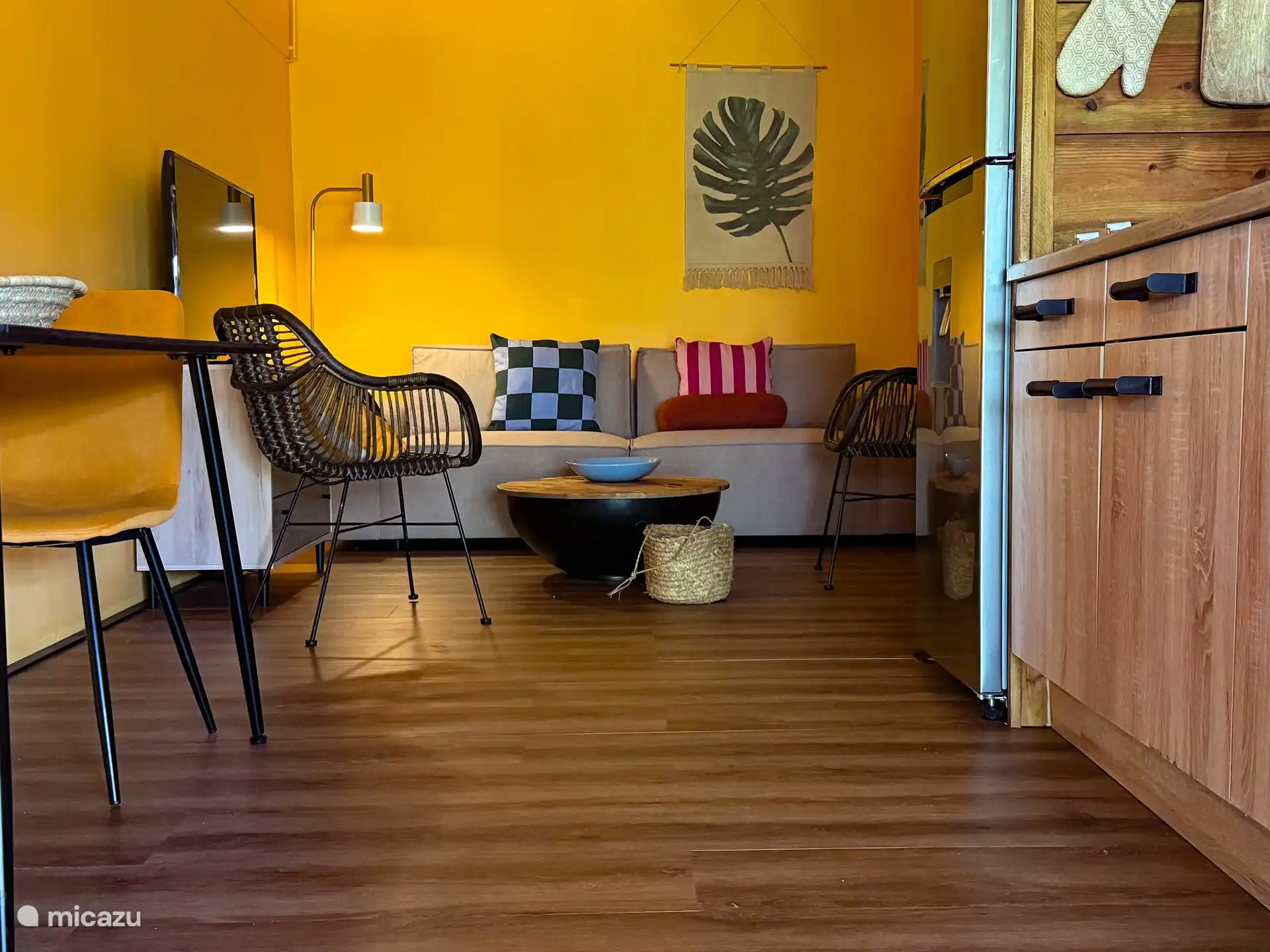 Sala de estar con sofá salón y 2 sillas, mesa de comedor y gran armario de madera, cocina abierta.