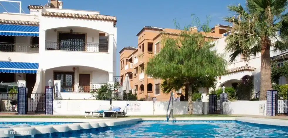 Zwembad met op de achtergrond het appartementencomplex