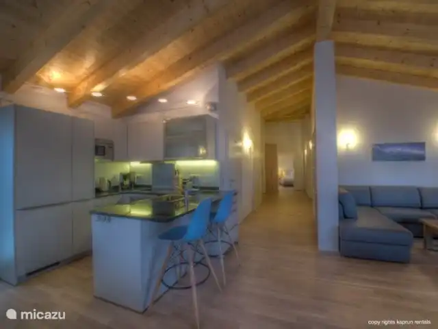 Residencia Kitzsteinhornblick Top2 en Austria, Salzburgo, Zell am See - penthouse Los techos altos con vigas de madera dan la máxima sensación de un ático. La maravillosa sala de estar abierta con chimenea, la espaciosa sala de estar y la lujosa cocina la completan. Desde el sofá puede recordar unas vacaciones exitosas, mientras disfruta de un refrigerio.