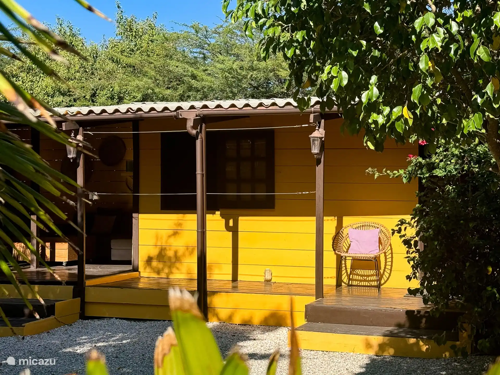 Amplia terraza sombreada con sofás, tumbonas, una gran mesa de comedor y barbacoa.