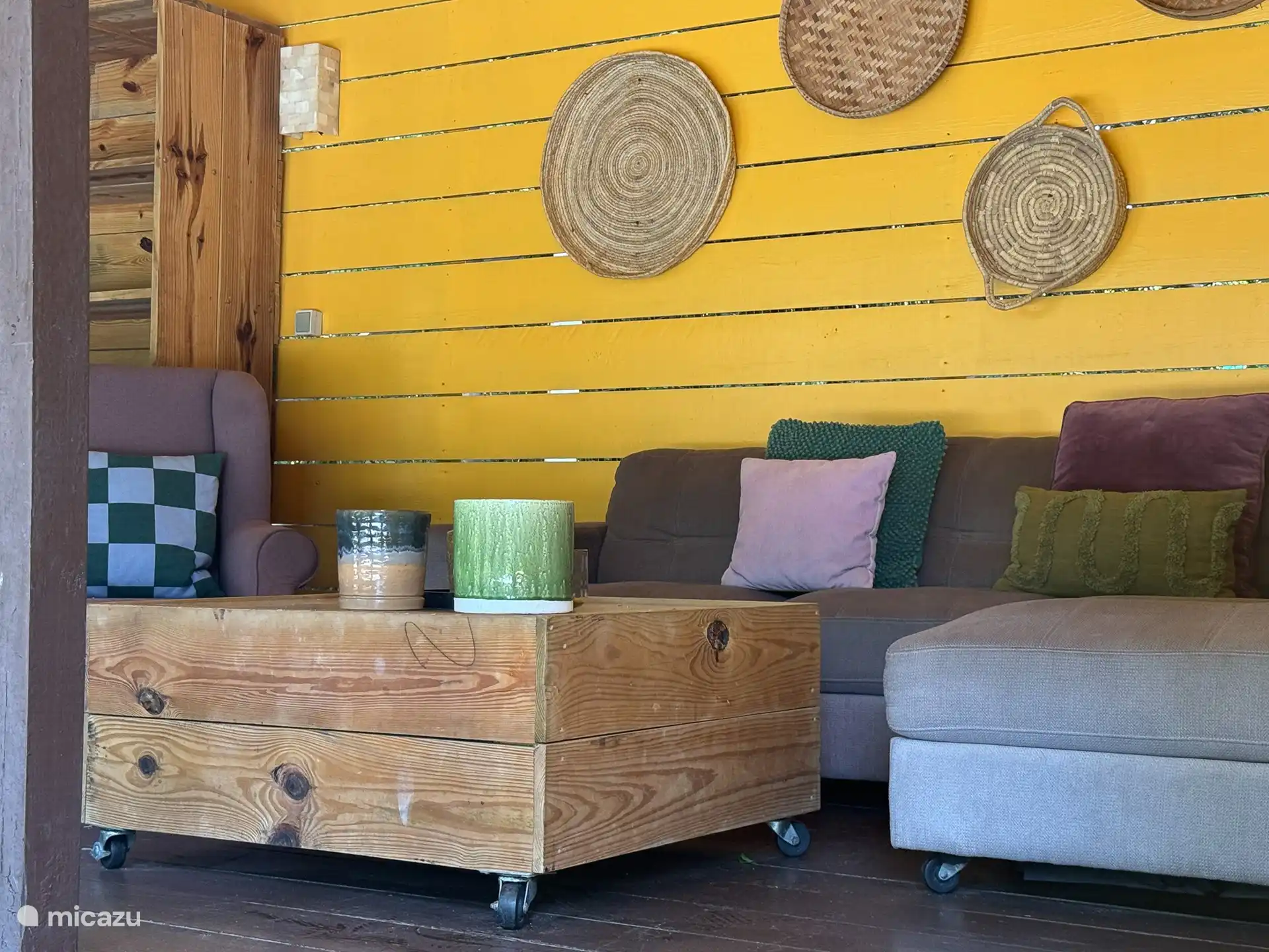 Amplia terraza sombreada con sofás, sillones, una gran mesa de comedor y barbacoa.