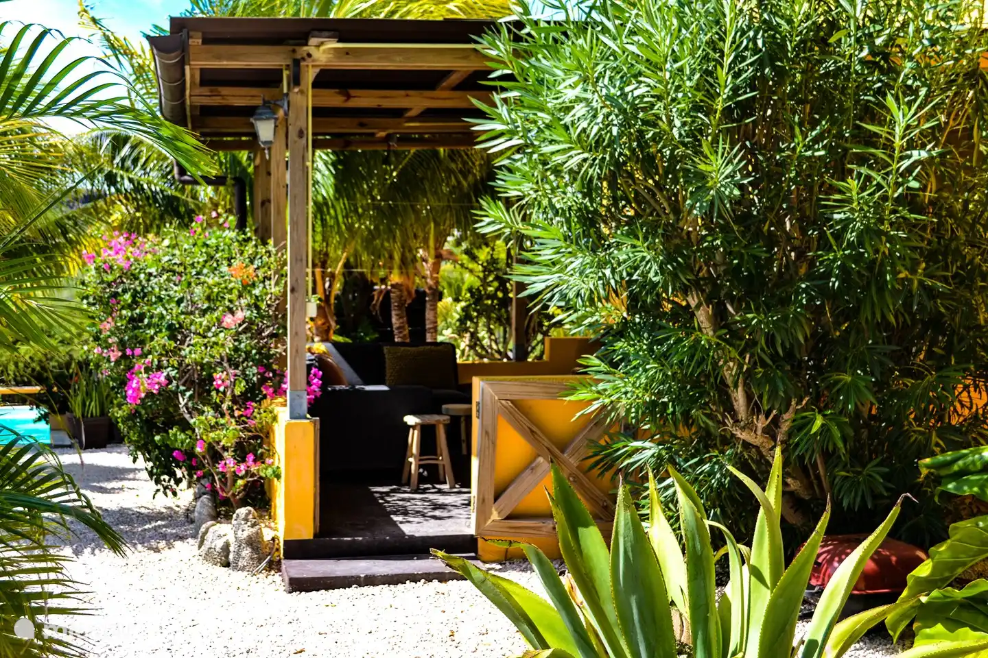 El apartamento con la terraza a la sombra en el jardín tropical. La terraza ofrece un sofá lounge, un sofá lounge, una gran mesa de comedor, barbacoa y una hermosa vista de las colinas de Curazao.