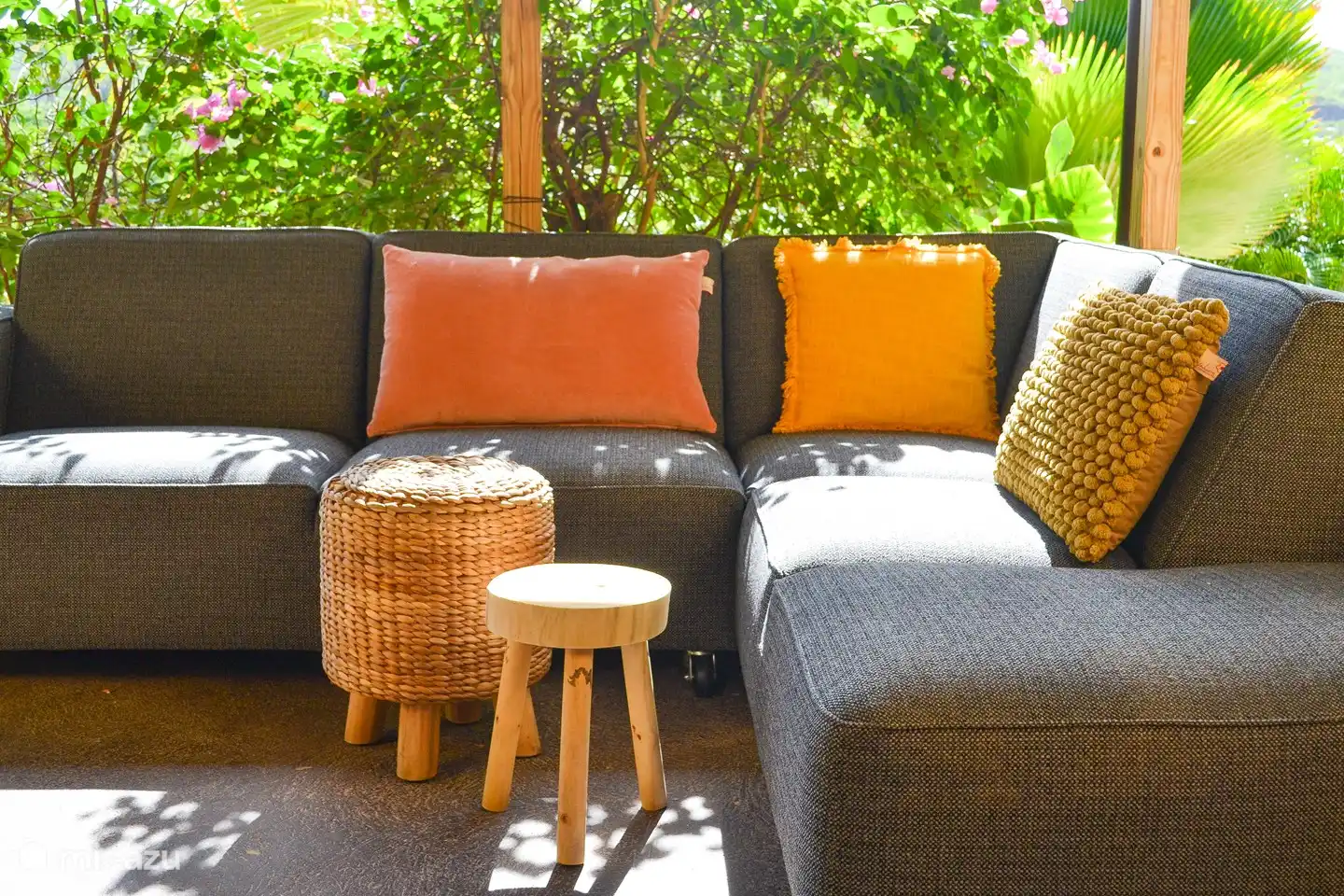 El apartamento con la terraza a la sombra en el jardín tropical. La terraza ofrece un sofá lounge, un sofá lounge, una gran mesa de comedor, barbacoa y una hermosa vista de las colinas de Curazao.