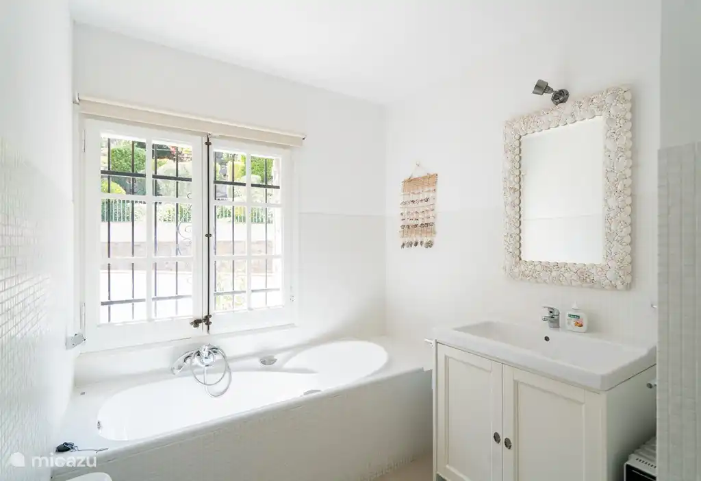 Salle de bain avec baignoire, cabine de douche, lavabo et toilettes. Un autre WC séparé dans le couloir.