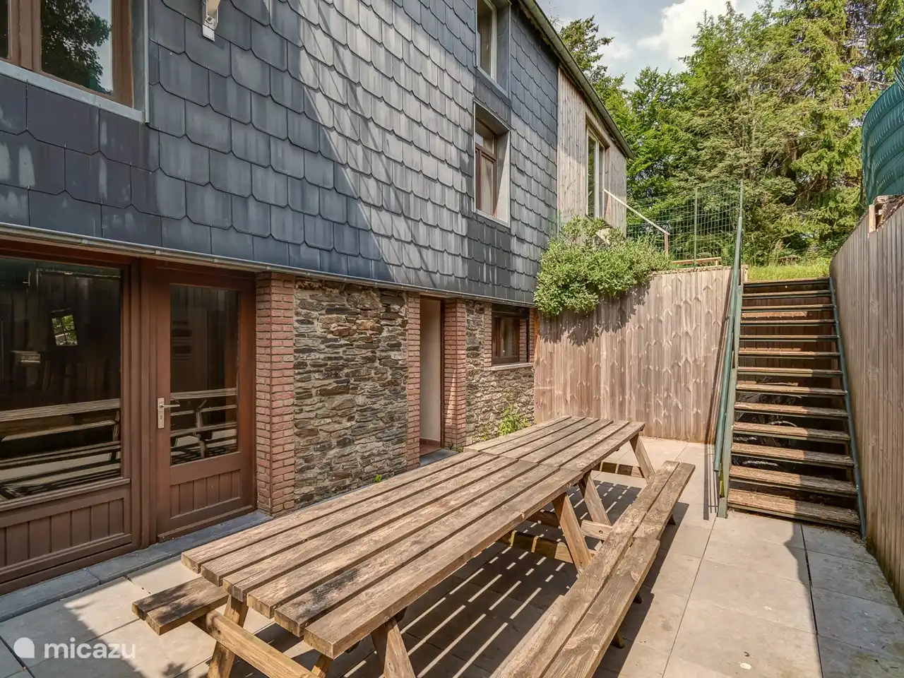 Terras, naast de keuken. Trap naar een stukje tuin/gras. 