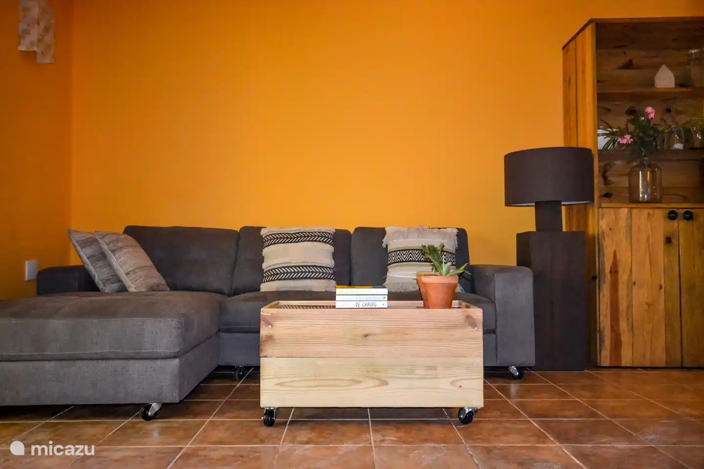 Sala de estar con sofá salón y TV digital, cocina abierta.