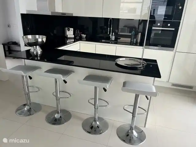 eine L-Küche mit Theke, Einbau-Geschirrspüler, Kühl- / Gefrierschrank, Elektroherd, Backofen und Mikrowelle