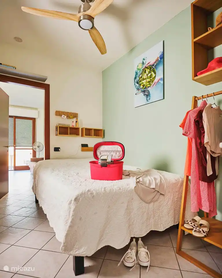 Dormitorio con ventilador de techo, toma de corriente en la cama, lámpara de lectura, armarios y perchero. Cuarto de baño en suite