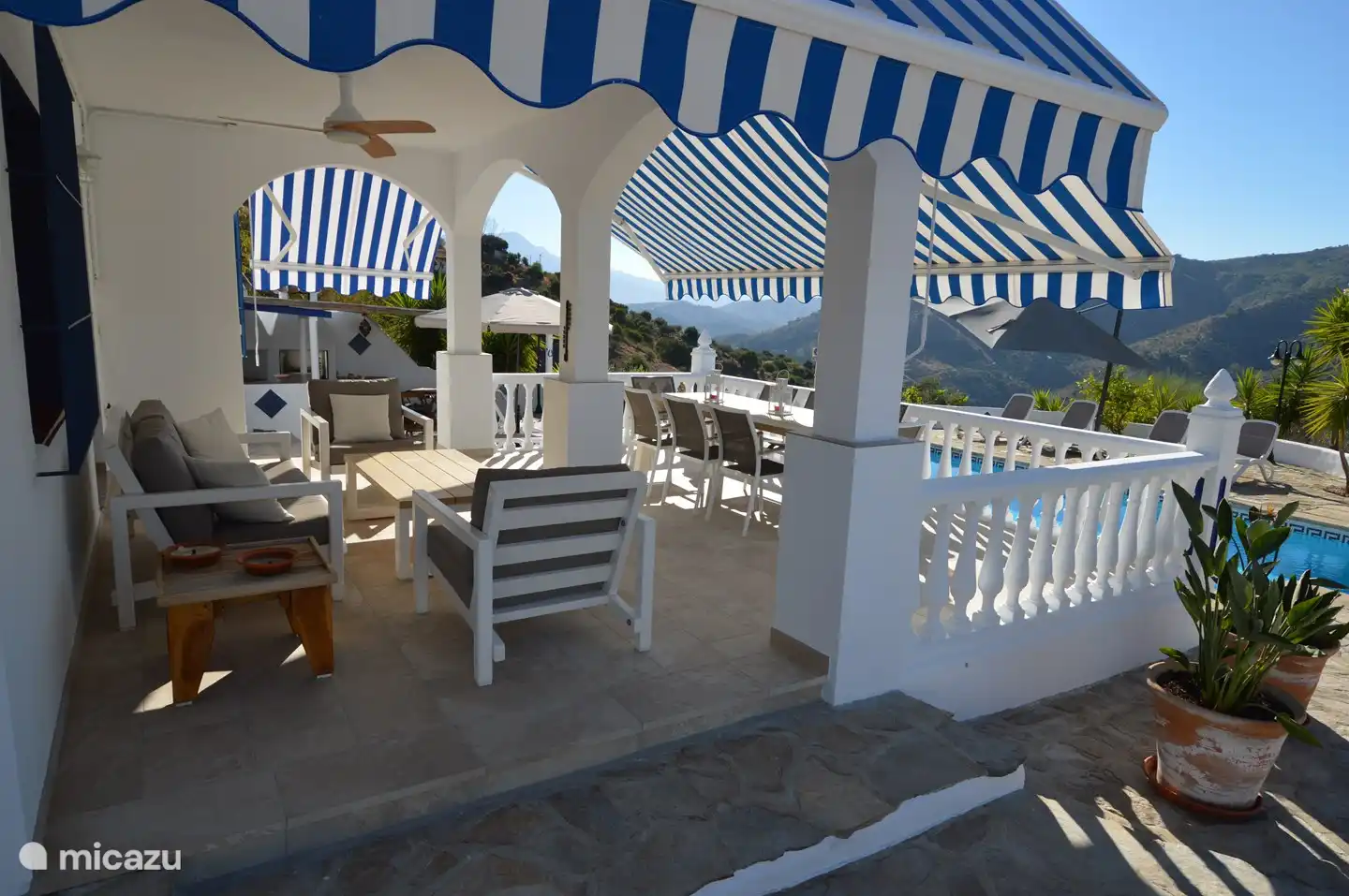 C&#243;modo juego de sal&#243;n y gran mesa de comedor en la terraza con toldos.