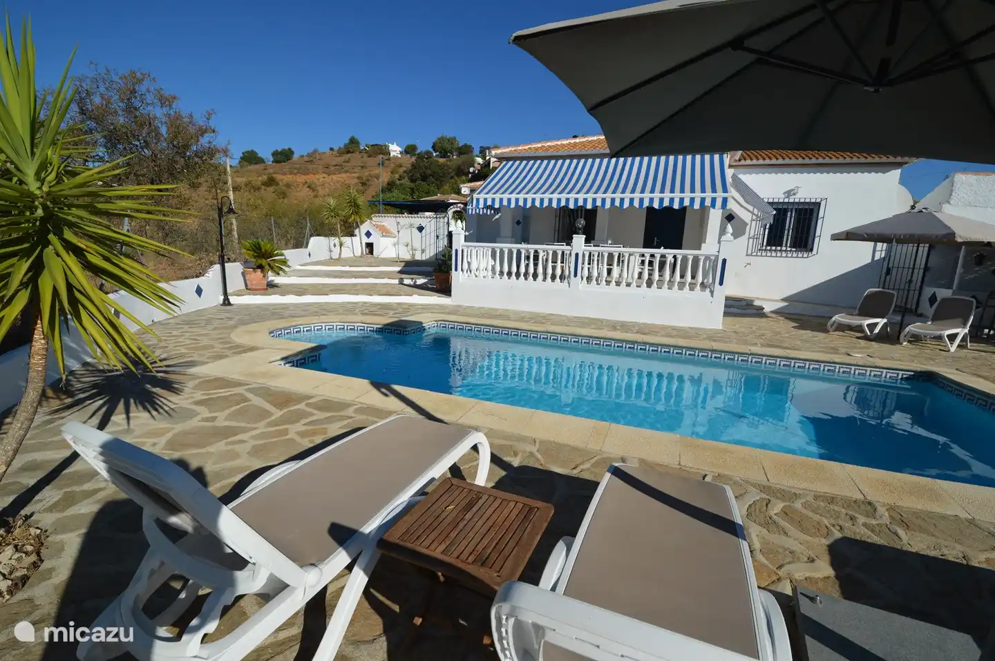 Piscina con escalera de acceso (noroeste), c&#243;modas tumbonas y gran sombrilla.