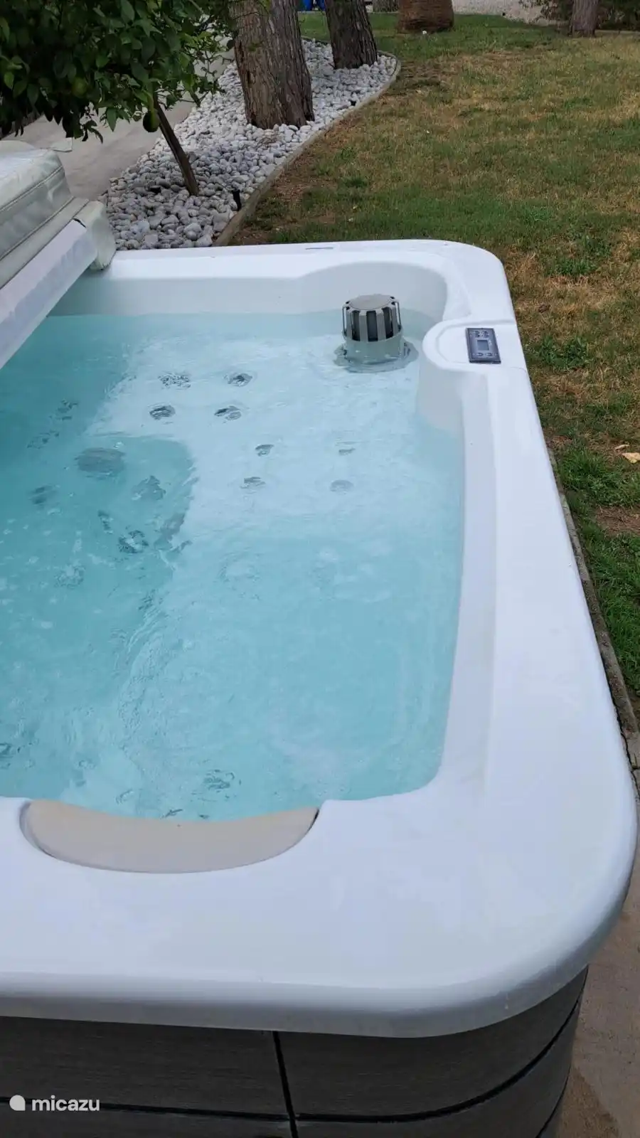 Grand jacuzzi fixe avec système de filtrage automatique et coussin de couverture solide.