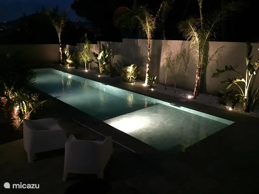 La piscine et le reste de la maison et du jardin sont éclairés.