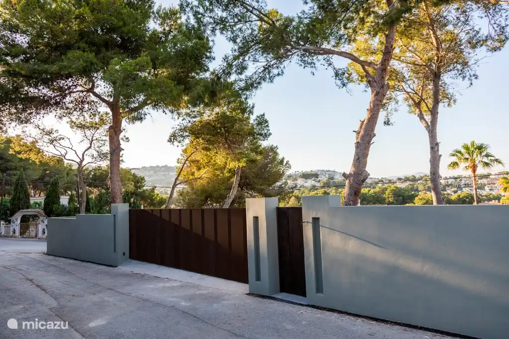 Portail avec parking privé derrière sur le terrain complètement plat avec vue sur la banlieue (environ 1000m2).