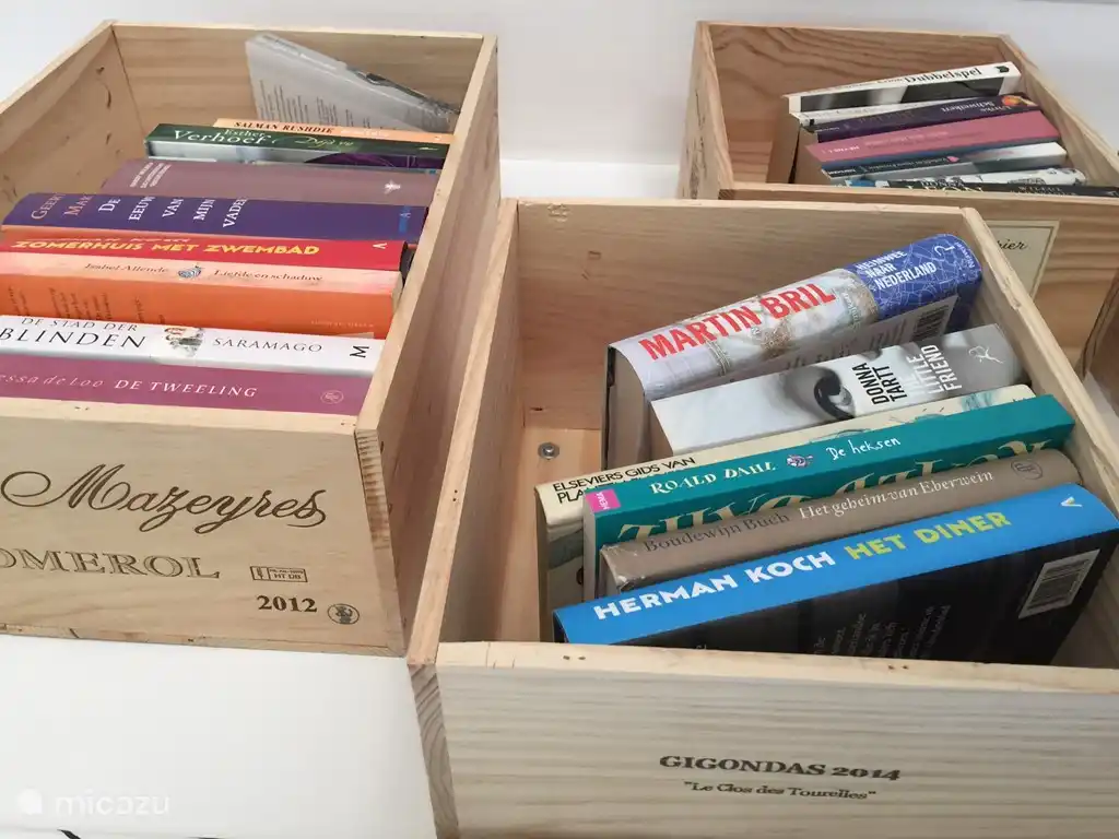 Boeken in wijnkisten aan de muur. 