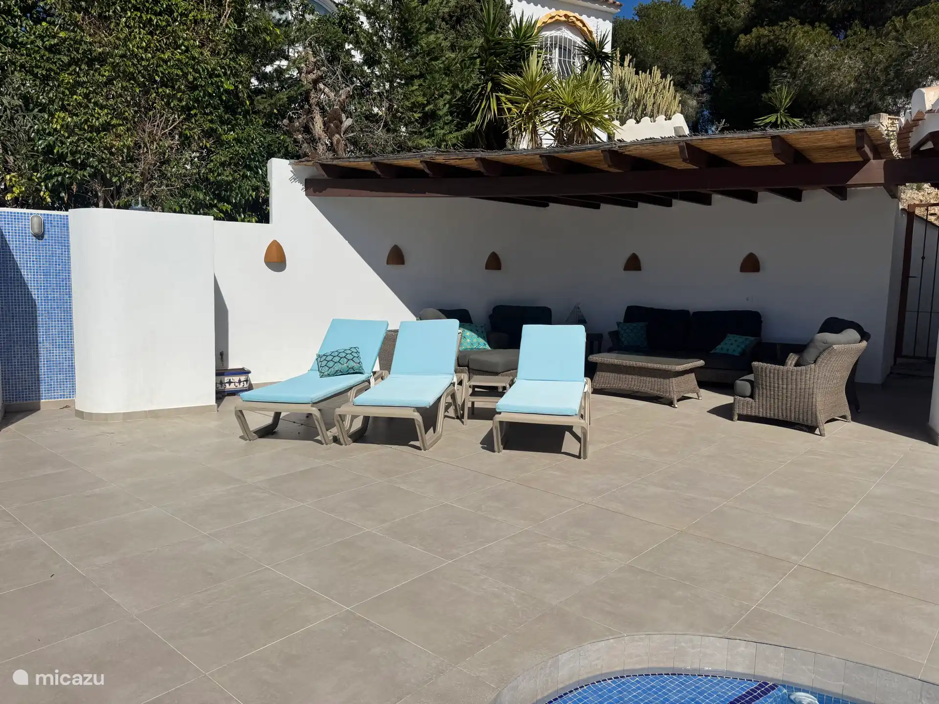 Überdachte Terrasse mit Lounge-Set und schönen Liegestühlen. 