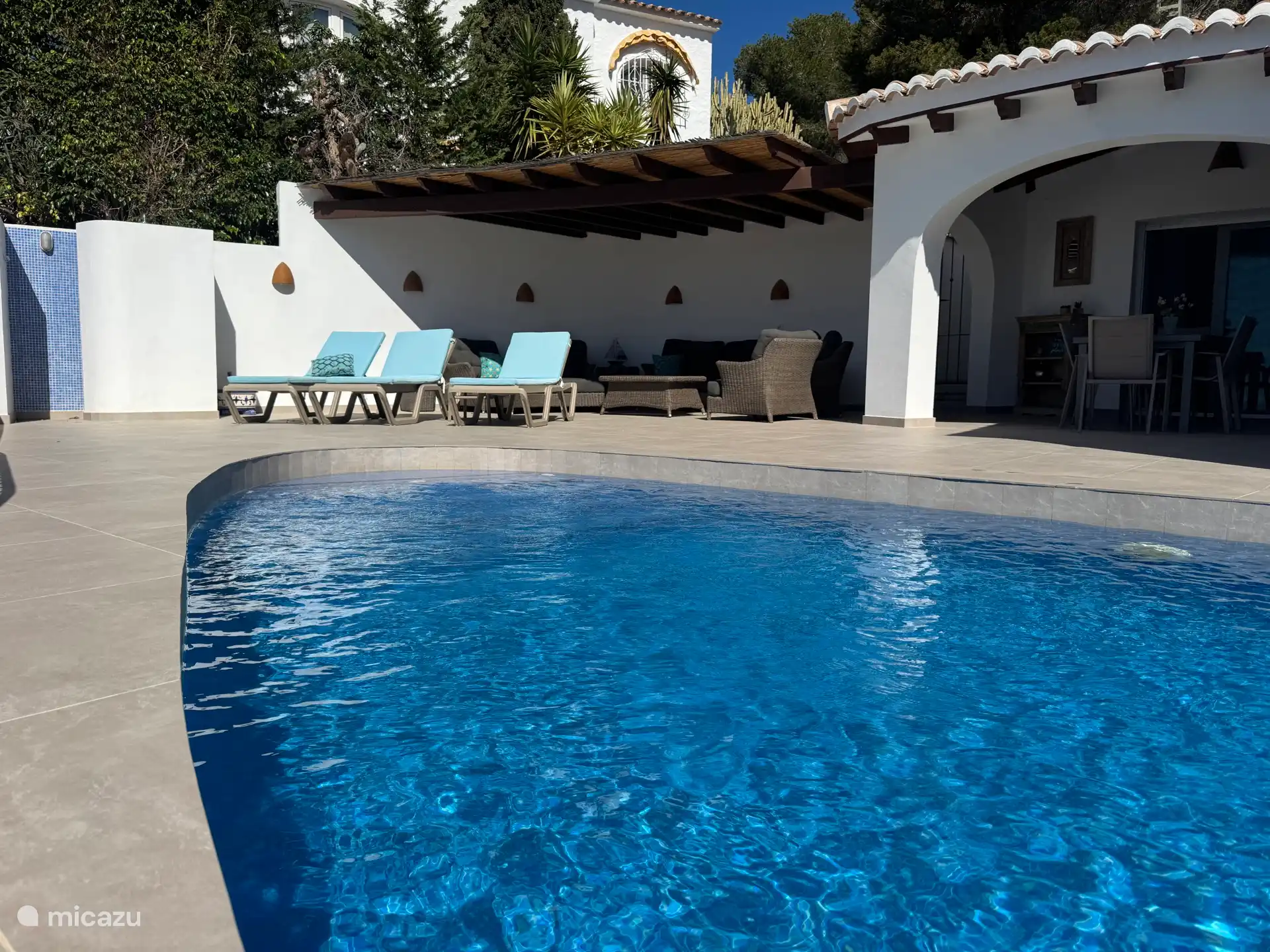 die Terrasse mit drei luxuriösen Sonnenliegen und dem Swimmingpool und der Außendusche 