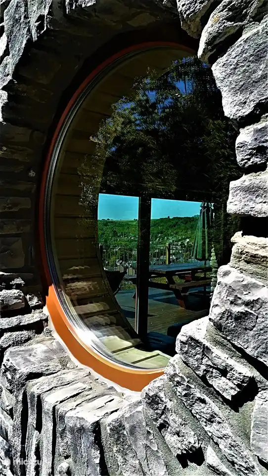 Blick durch das runde Seitenfenster auf die Südterrasse auf der Rückseite.