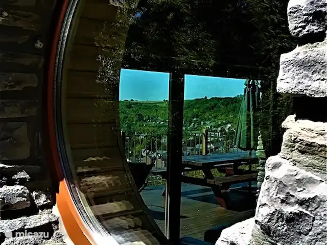 Wellness Chalet ROOS in Durbuy | Belgique, Ardennes, Bomal-sur-Ourthe - villa En regardant par la fenêtre latérale ronde sur la terrasse sud à l’arrière.