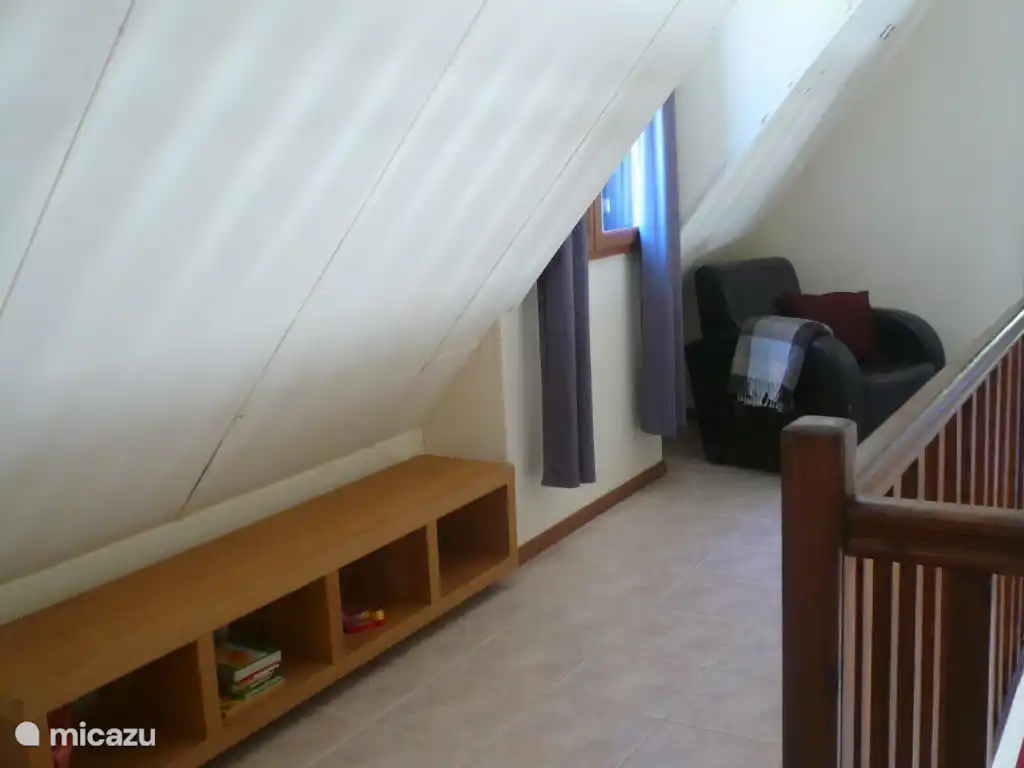 Loft mit Ledersessel und Schrank mit Büchern in verschiedenen Sprachen (für Jung und Alt) und Brettspielen