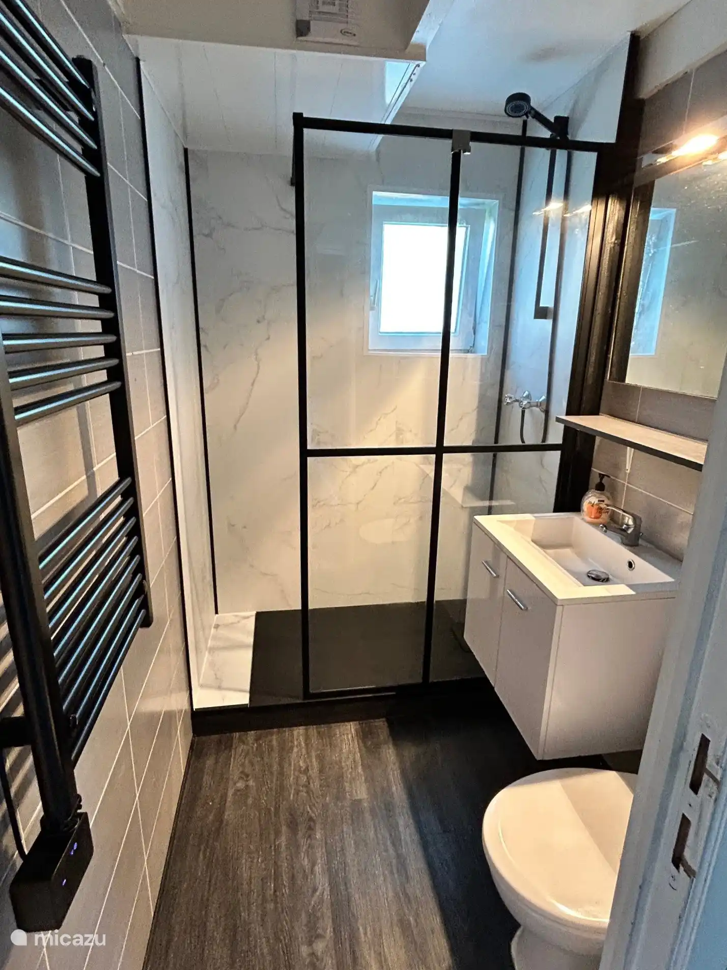 Badezimmer mit ebenerdiger Dusche, Waschbecken, WC und Handtuchtrockner