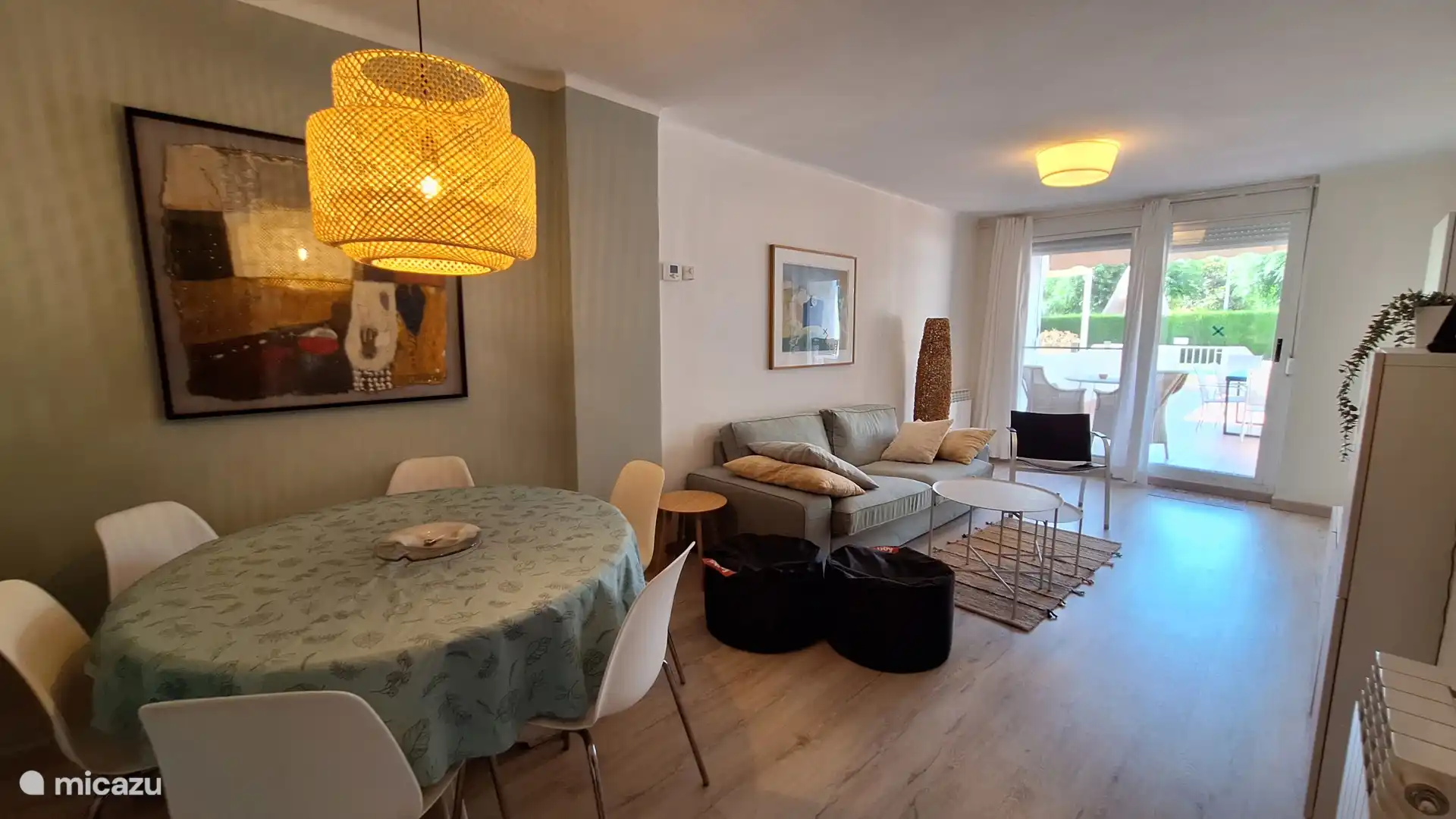 Woonkamer met eettafel voor 6 personen, zitgedeelte, airco, smart tv en directe toegang tot het grote  privéterras. 