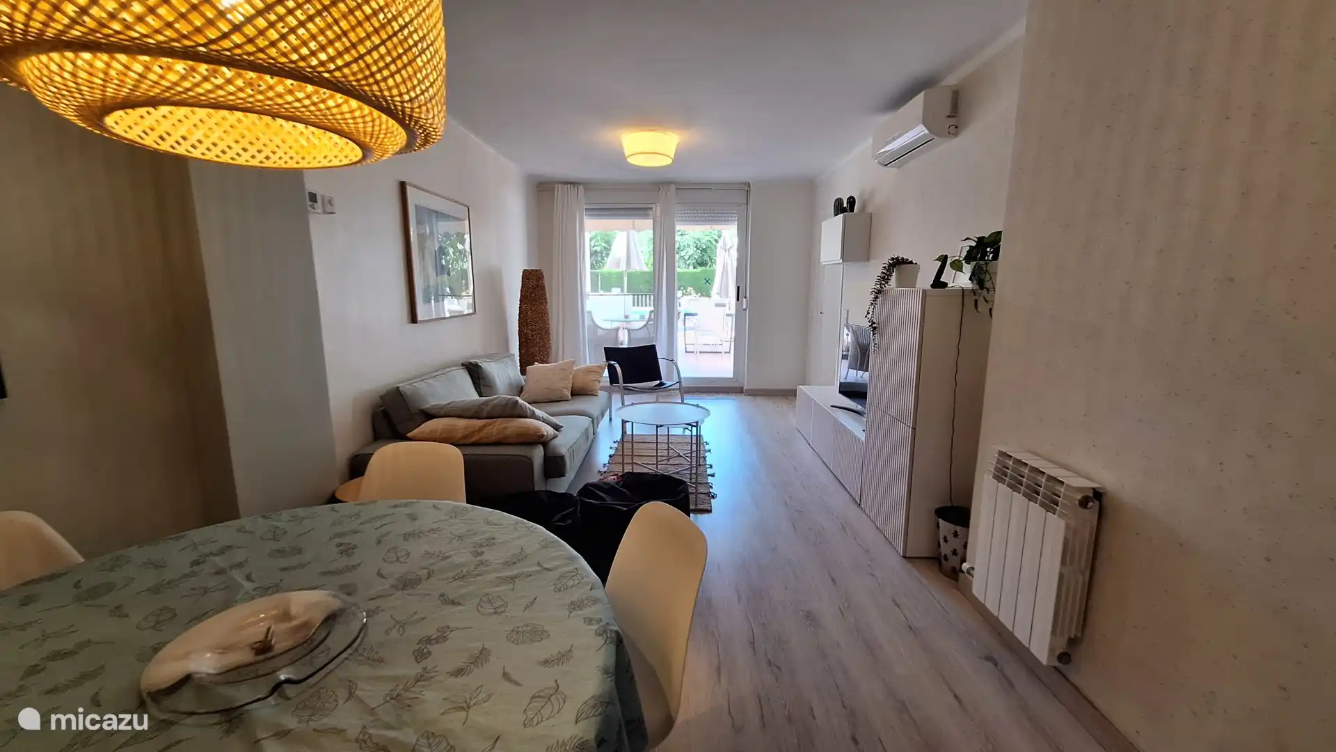 Woonkamer met eettafel voor 6 personen, zitgedeelte, airco en directe toegang tot het grote  privéterras. 