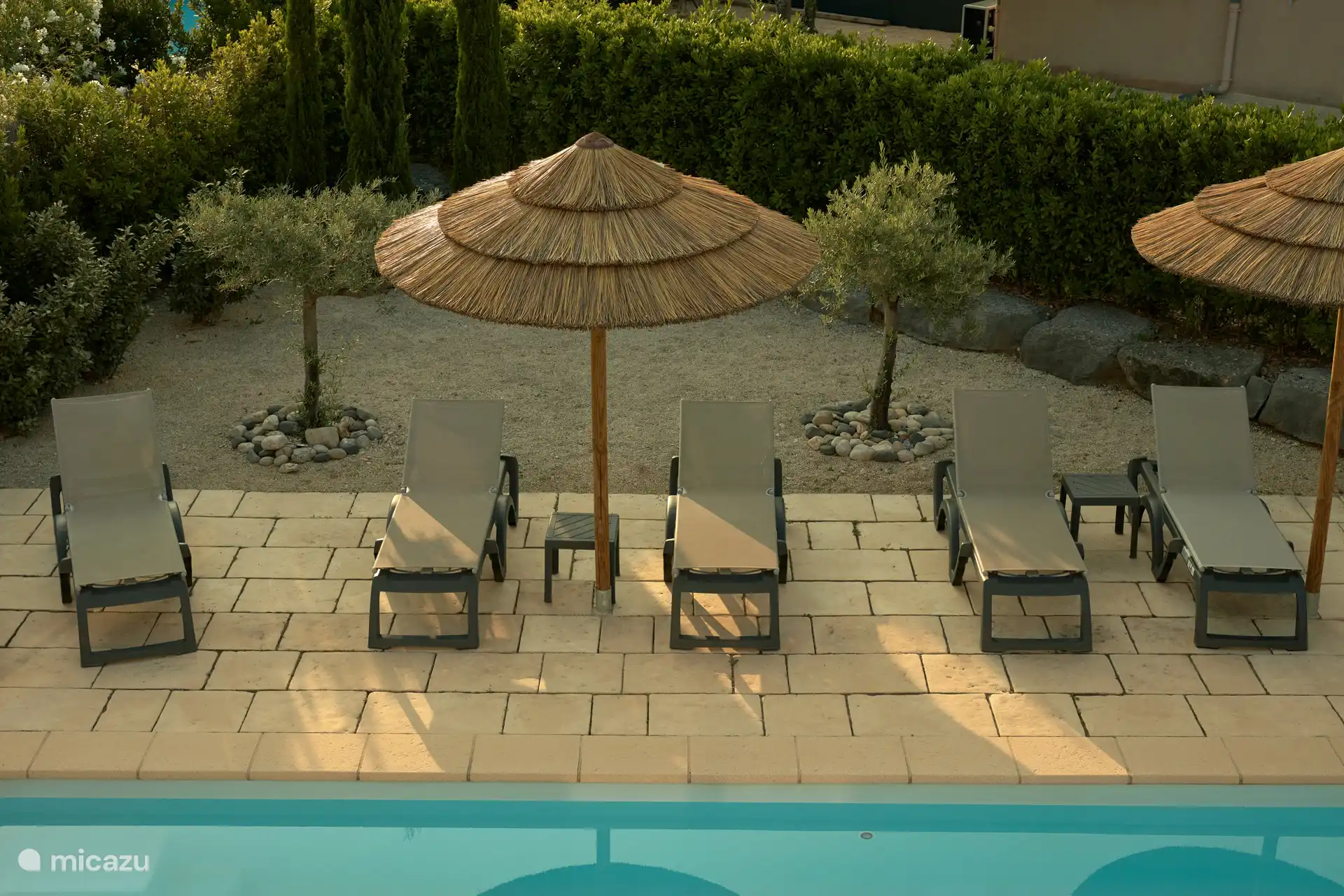 Sombrillas fijas con techo de paja y tumbonas ajustables.