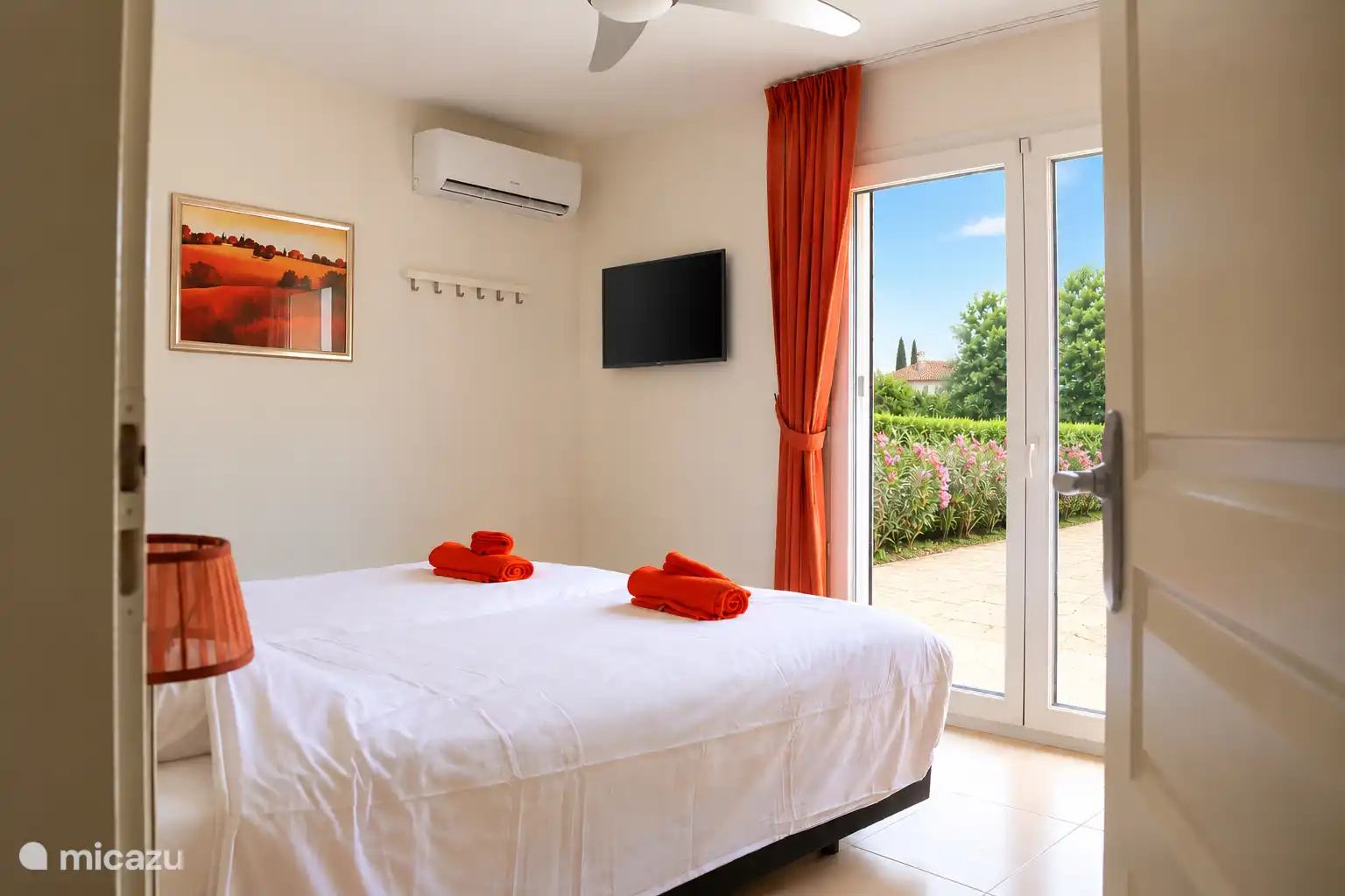 Master bedroom met tv, airco, kledingkast en nachtkastjes.
