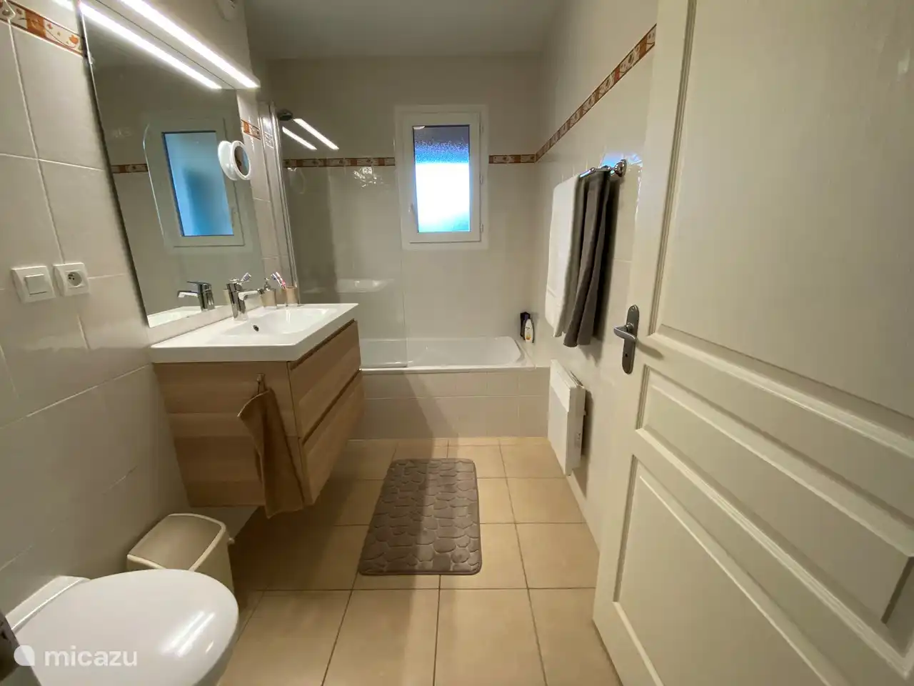 Beneden badkamer met ligbad/douche, luxe badmeubel met voldoende opbergmogelijkheden en een toilet.