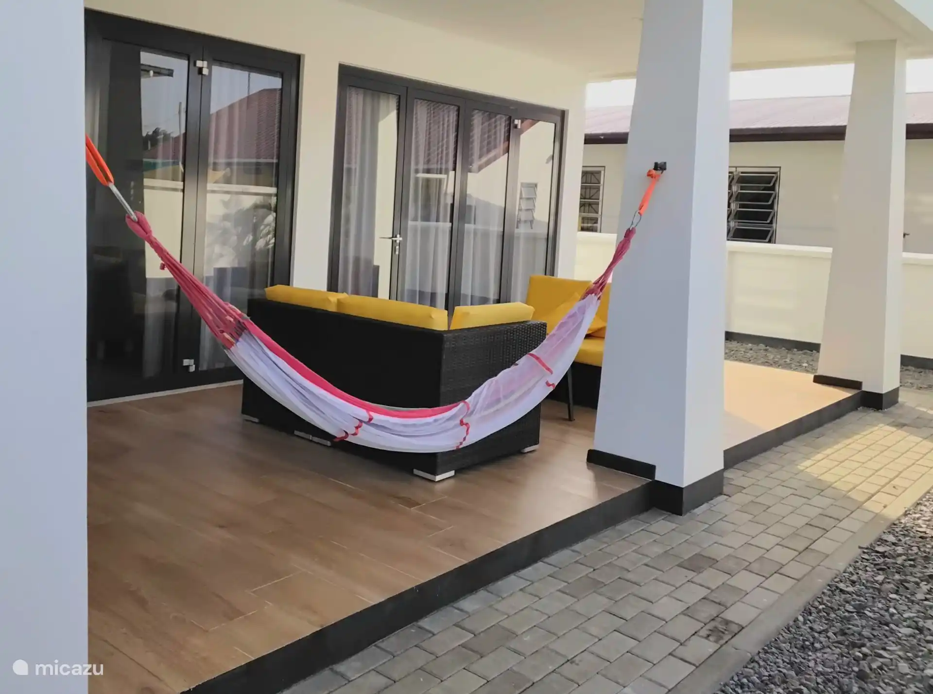 Die Terrassentüren bieten Zugang zur Terrasse mit Sitzgelegenheiten und Hängematte