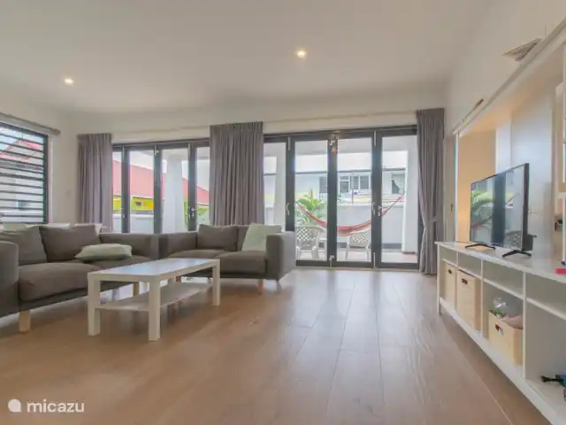 Location de Vacances Suriname, Paramaribo, Paramaribo, appartement - Icare IV le coin salon avec télévision intelligente et deux grands murs pliants vers l'extérieur.