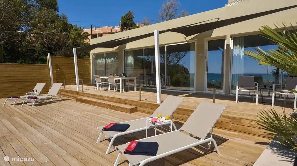 Holzterrasse mit Sonnenliegen und Sechs-Personen-Esstisch