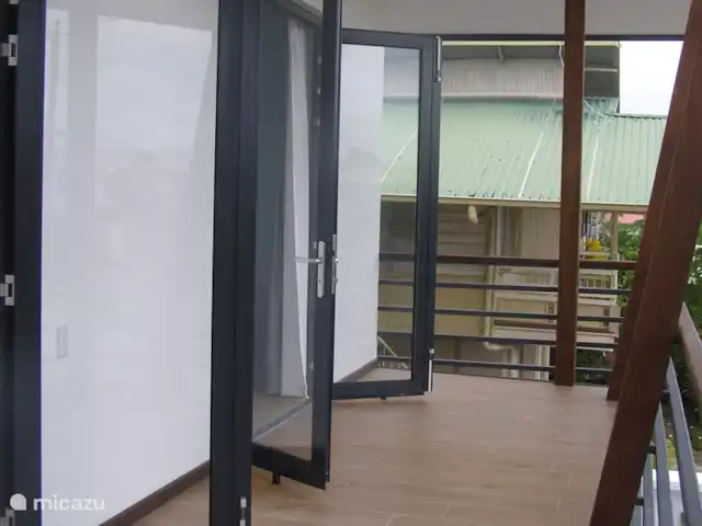 Location de Vacances Suriname, Paramaribo, Paramaribo, appartement - Icare VI Balcon à l'avant avec les portes ouvertes de la cuisine et de la chambre 3.