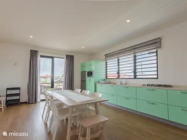 Location de Vacances Suriname, Paramaribo, Paramaribo, appartement - Icare VI À gauche de l'escalier se trouve une cuisine avec de nombreux appareils encastrés. vaisselle et ustensiles de cuisine.