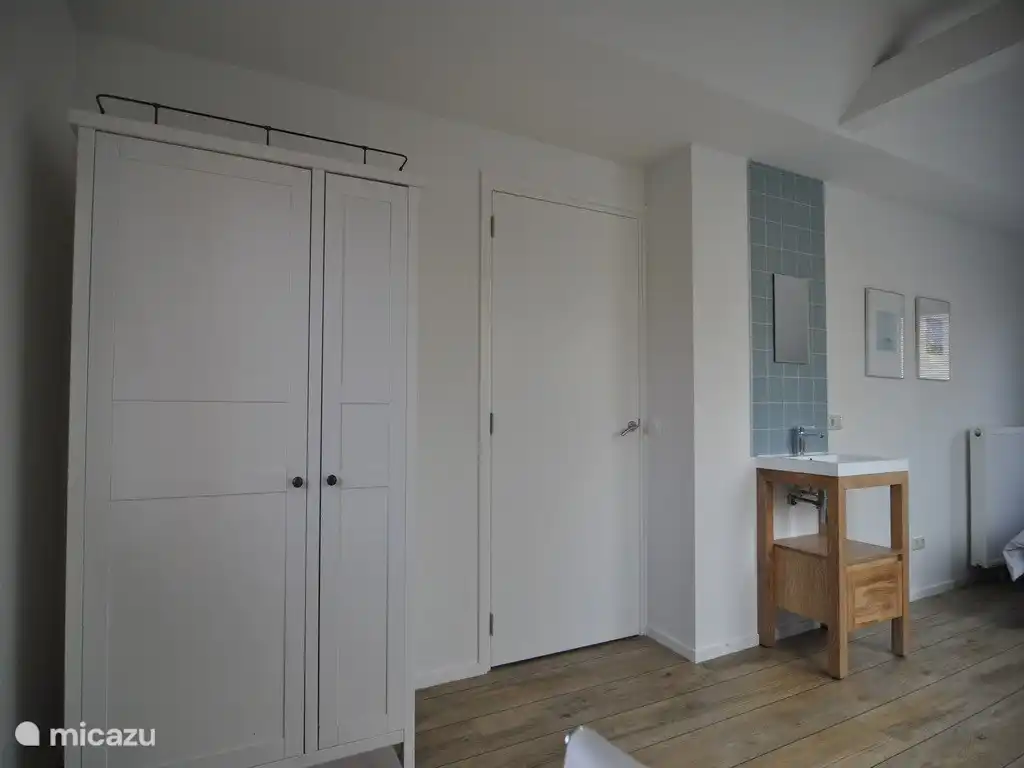 Geräumiges Schlafzimmer mit Waschbecken, Schreibtisch und Fernseher