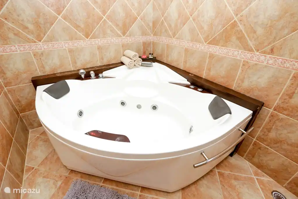 En-suite Badezimmer mit einer großen beleuchteten zwei Person Whirlpool, WC, großes Waschbecken und viel Stauraum