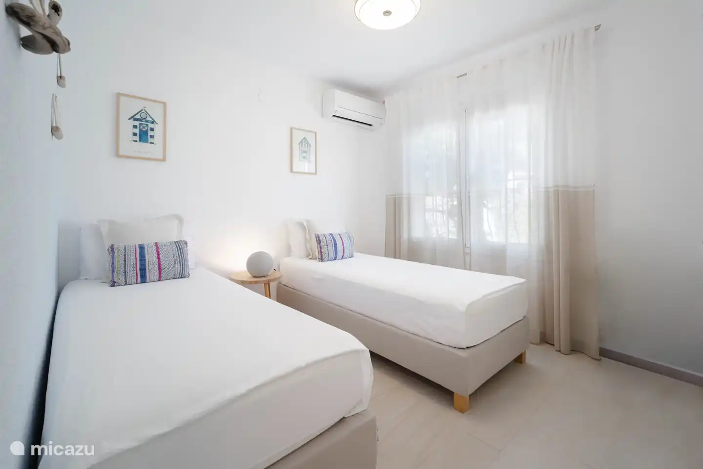 Geräumiges Schlafzimmer mit zwei Einzelbetten und Zugang zu einem modernen zweiten Badezimmer.